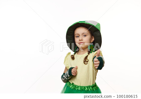 Adorable Irish little child girl wearing clover leaves earrings and green hat, showing thumb up, looking at camera, isolated over white background. Traditions, culture and national holiday in Ireland Adorable Irish little child girl wearing clover leaves earrings and green hat, showing thumb up, looking at camera, isolated over white background. Traditions, culture and national holiday in Ireland 100180615
