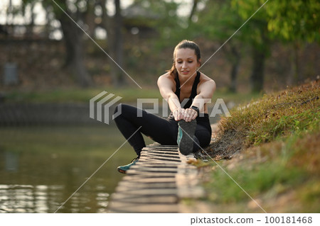 Sporty woman sporty woman stretching exercises near lake. Healthy lifestyle, sport and fitness concept 100181468