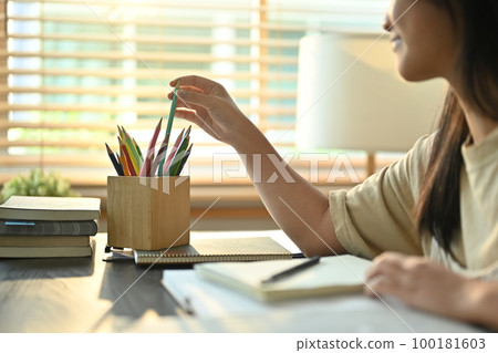 Cropped image of teenage asian woman doing homework, preparing for exam at home. Education concept 100181603
