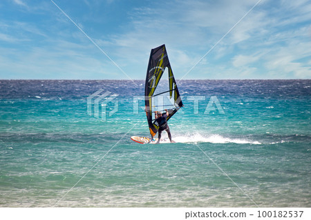 Wind surfer with black yellow transparent sails at Atlantic beach Risco del Paso in east of Fuerteventura 100182537
