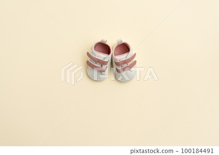 Baby pink shoes on yellow paper background with copy space. Baby clothes concept. Top view, flat lay Baby pink shoes on yellow paper background with copy space. Baby clothes concept. Top view, flat lay 100184491