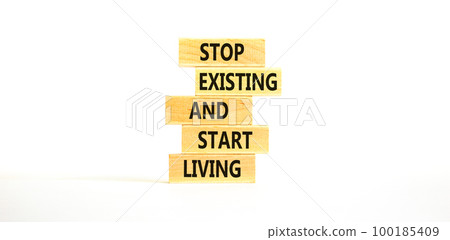 Stop existing start living symbol. Concept words Stop existing and start living on wooden blocks. Beautiful white table white background. Business Stop existing start living concept. Copy space. 100185409