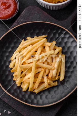 Delicious crispy french fries with salt and spices on a dark concrete background Delicious crispy french fries with salt and spices on a dark concrete background 100186218