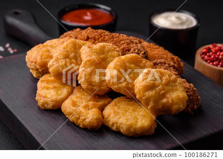 Delicious crispy chicken nuggets with salt and spices on a dark concrete background 100186271