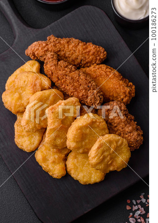 Delicious crispy chicken nuggets with salt and spices on a dark concrete background Delicious crispy chicken nuggets with salt and spices on a dark concrete background 100186273