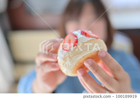 A woman eating a large fruit sandwich filled with whipped cream and strawberries Local gourmet food for a camper trip 100189919