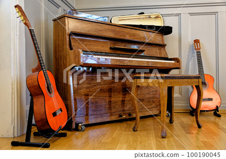 Guitar, piano stool and a piano in a vintage house 100190045