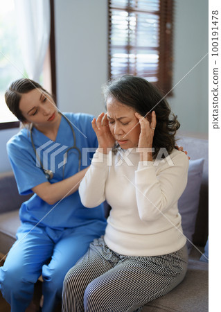 Portrait of a female doctor talking to an elderly patient showing headache 100191478
