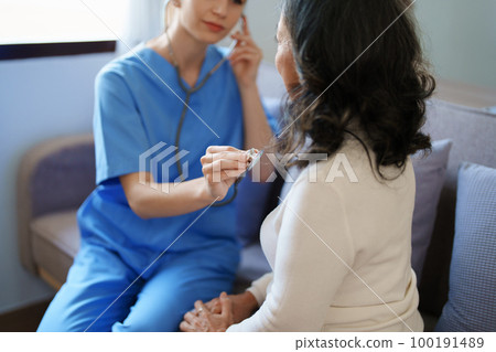 Portrait of a female doctor using a stethoscope to check the pulse of an elderly patient 100191489
