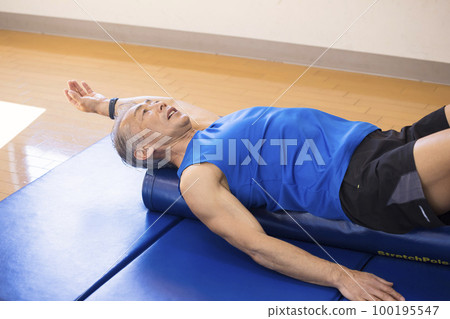 Middle-aged man stretching with a stretch pole Middle-aged man stretching with a stretch pole 100195547