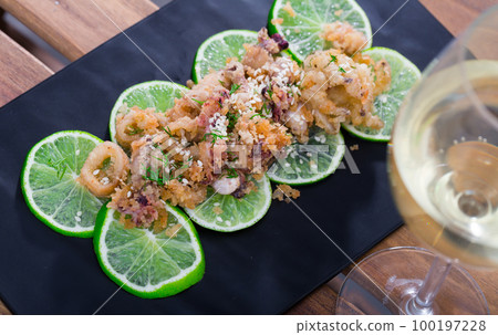 Squid and cuttlefish tempura on lime slices with wine 100197228