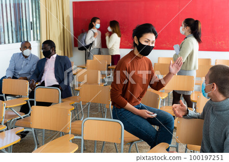 Portrait of kazakh woman and european man students with surgical medical masks discussing interesting topics ,protect Covid-19 or corona virus disease , healthcare concept 100197251