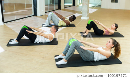 Sporty people training pilates at group class Sporty people training pilates at group class 100197371