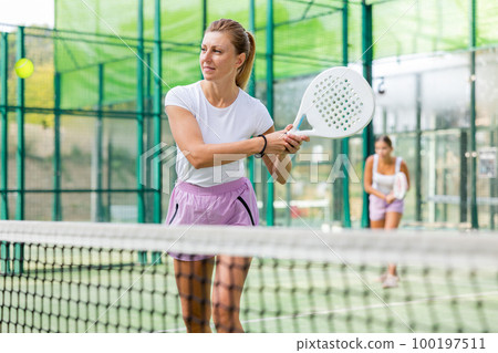 European woman padel tennis player trains on the outdoor court European woman padel tennis player trains on the outdoor court 100197511