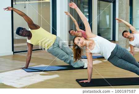 Sporty people doing stretching workout during pilates training 100197587