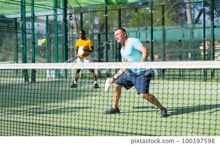 Man playing padel tennis on court 100197598