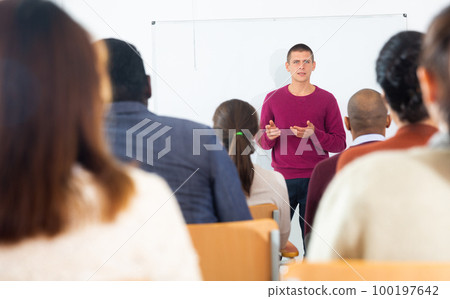 Man lecturing to adult students at auditorium 100197642