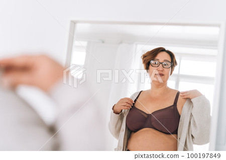 Self loving middle aged woman in underwear looking at mirror in badroom at home Self loving middle aged woman in underwear looking at mirror in badroom at home 100197849