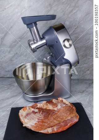 Electric eat grinder and fresh meat on kitchen table. Preparation of minced meat 100198357