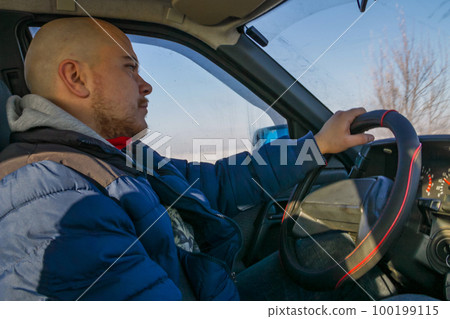 Young man driving a car on winter road. Inside view Young man driving a car on winter road. Inside view 100199115