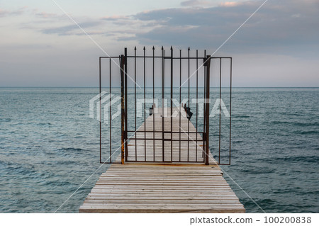 Closed iron gates on wooden pier in blue sea. Koktebel. Crimea 100200838