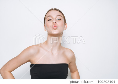Beauty portrait of funny young girl with fresh skin tone showing kiss on white background isolated Beauty portrait of funny young girl with fresh skin tone showing kiss on white background isolated 100202304