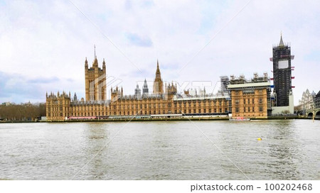 The partially repaired British Houses of Parliament standing on the banks of the River Thames and the fully repaired clock tower. England London 100202468