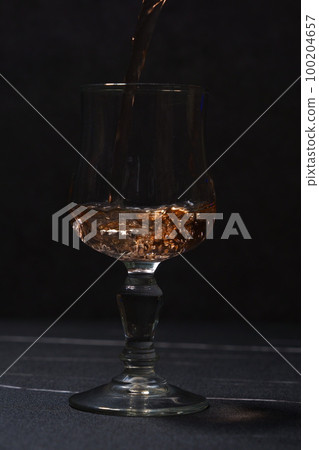 Pouring rosé wine into a wine glass Pouring rosé wine into a wine glass 100204657