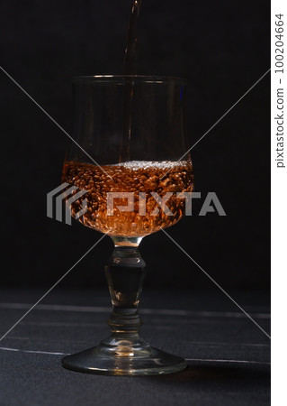 Pouring rosé wine into a wine glass 100204664