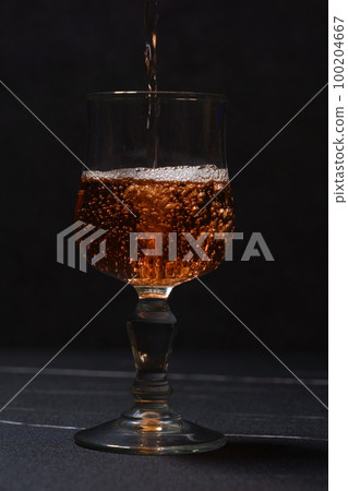 Pouring rosé wine into a wine glass 100204667