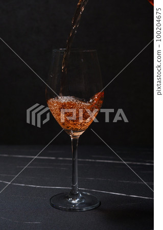 將桃紅葡萄酒倒入酒杯中 將桃紅葡萄酒倒入酒杯中 100204675