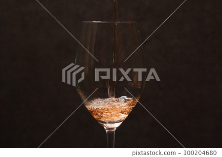 Pouring rosé wine into a wine glass 100204680