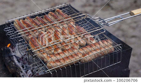 Sausages are fried on the grill in nature Sausages are fried on the grill in nature 100206706