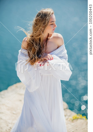 Portrait of a blond woman at the sea, a woman makes photos for memory from a trip to the sea to show to friends. Portrait of a blond woman at the sea, a woman makes photos for memory from a trip to the sea to show to friends. 100208443