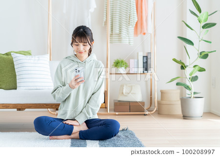 A young woman using a smartphone in the living room 100208997