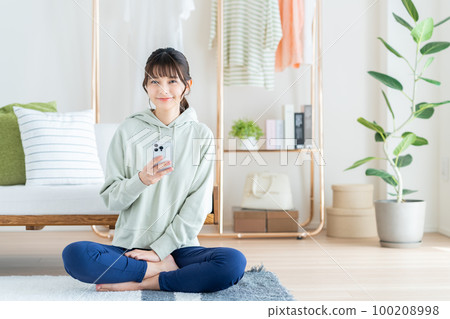 A young woman using a smartphone in the living room 100208998