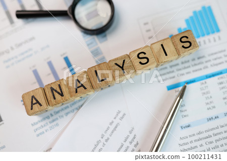 Wooden cubes with word analysis, magnifying glass and pen on financial report. Wooden cubes with word analysis, magnifying glass and pen on financial report. 100211431