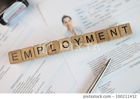 Wooden cubes with word employment, pen and stamp approved on employee's resume. Wooden cubes with word employment, pen and stamp approved on employee's resume. 100211432