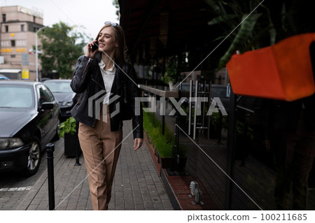 successful young adult female student walking around the city and talking on the phone successful young adult female student walking around the city and talking on the phone 100211685