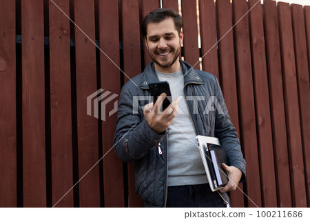 european freelance man chatting on the phone on the street 100211686