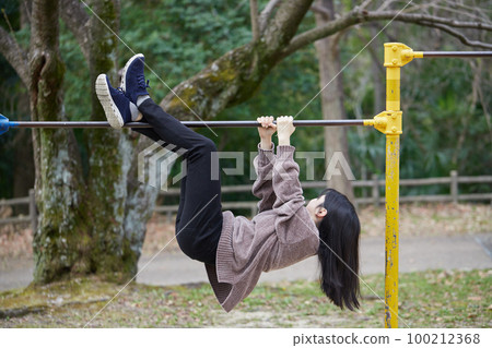 A female junior high school student exercising with a horizontal bar in a spring park A female junior high school student exercising with a horizontal bar in a spring park 100212368