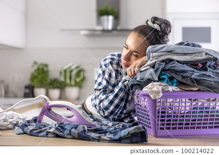 Wife fell asleep on a pile of clothes in the basket keeping the iron on next to her 100214022