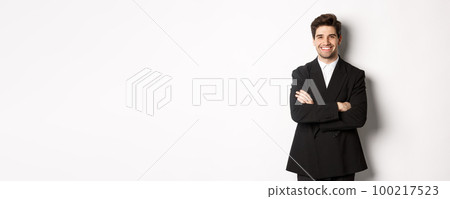 Handsome and confident bearded man, standing in formal suit with hands crossed on chest, smiling satisfied, attend party or work event, standing over white background 100217523