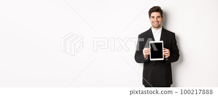 Portrait of handsome businessman in trendy suit, showing digital tablet screen and smiling, standing against white background Portrait of handsome businessman in trendy suit, showing digital tablet screen and smiling, standing against white background 100217888
