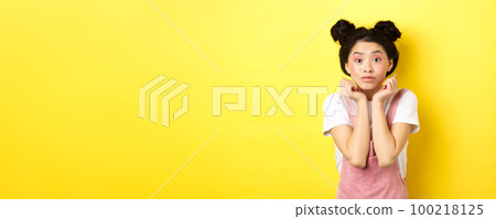 Cute teenage asian girl with beauty makeup, listen with interest, lean on hands and looking excited at camera, standing on yellow background Cute teenage asian girl with beauty makeup, listen with interest, lean on hands and looking excited at camera, standing on yellow background 100218125