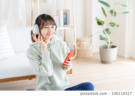 在客廳裡聽音樂的年輕女人 100218527