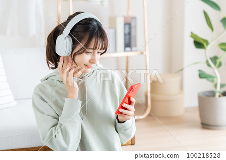 Young woman listening to music in the living room Young woman listening to music in the living room 100218528