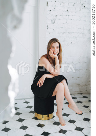 Fashion portrait of young woman with long hair on evening elegant black dress in white interior 100218710