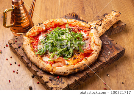 Oven baked pizza with mozzarella cheese, dried ham, tomatoes, balsamic vinegar and arugula Oven baked pizza with mozzarella cheese, dried ham, tomatoes, balsamic vinegar and arugula 100221717