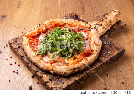 Oven baked pizza with mozzarella cheese, dried ham, tomatoes, balsamic vinegar and arugula Oven baked pizza with mozzarella cheese, dried ham, tomatoes, balsamic vinegar and arugula 100221718